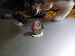 Papercraft fairy shaped like an ice cream cone, with cat in the background